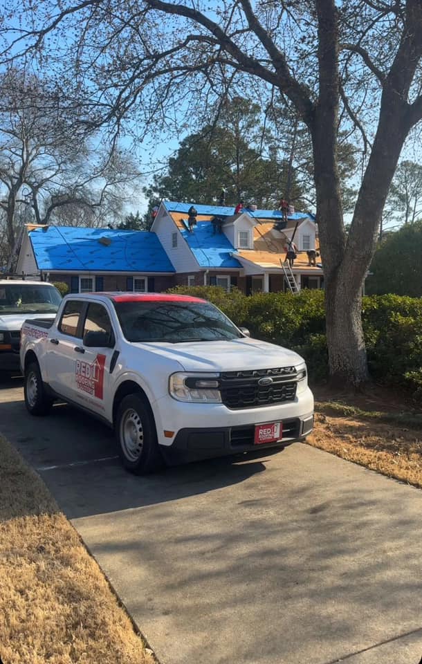 Red Roofing crew truck arriving at an Atlanta job site